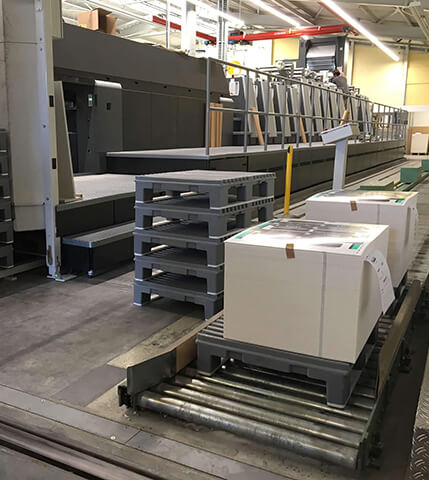 One stack of Jeco pallets next to Jeco pallets loaded with paper in a printing environment